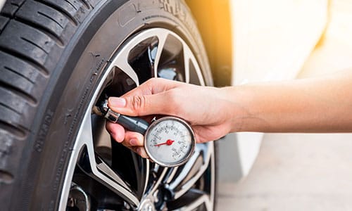 Close up of a man checking tyre pressure to help fleet save fuel